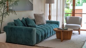 A teal sofa with cushions, a wooden coffee table, a white chair, and a potted plant. - Villa BUMI - Designer Villa 10 min to the Beach (Bali)