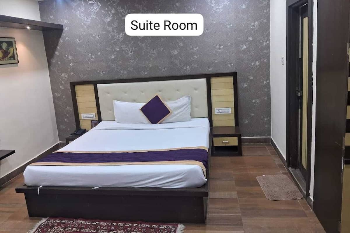 A suite room with a bed, bedside tables, a ceiling fan, and a door.