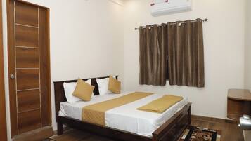 A bedroom with a wooden bed, white bedding, brown curtains, and a ceiling fan.