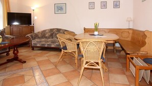 Een woonkamer met een televisie, bank, eettafel en stoelen.