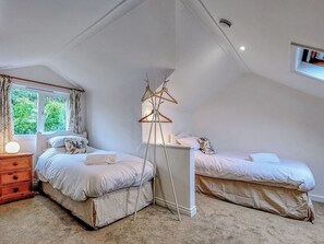A bedroom with two beds, a bedside table, a lamp, and a window with curtains. - 4 bedroom accommodation in Thornton Watlass, near Masham (Thornton Watlass, near Masham)