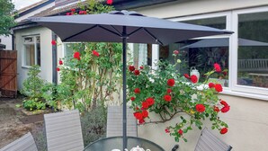 A glass table with chairs and a tray of tea set under an umbrella. - 4 bedroom accommodation in Thornton Watlass, near Masham (Thornton Watlass, near Masham)