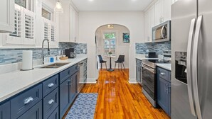 A modern kitchen with white cabinets, stainless steel appliances, and a wooden floor.