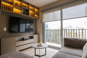 A modern living room with a flat-screen TV, a round coffee table with a book and a yellow object, a sofa, and a balcony with a railing. - w Prestigious 3BR w Great Balcony in Miraflores (Lima)