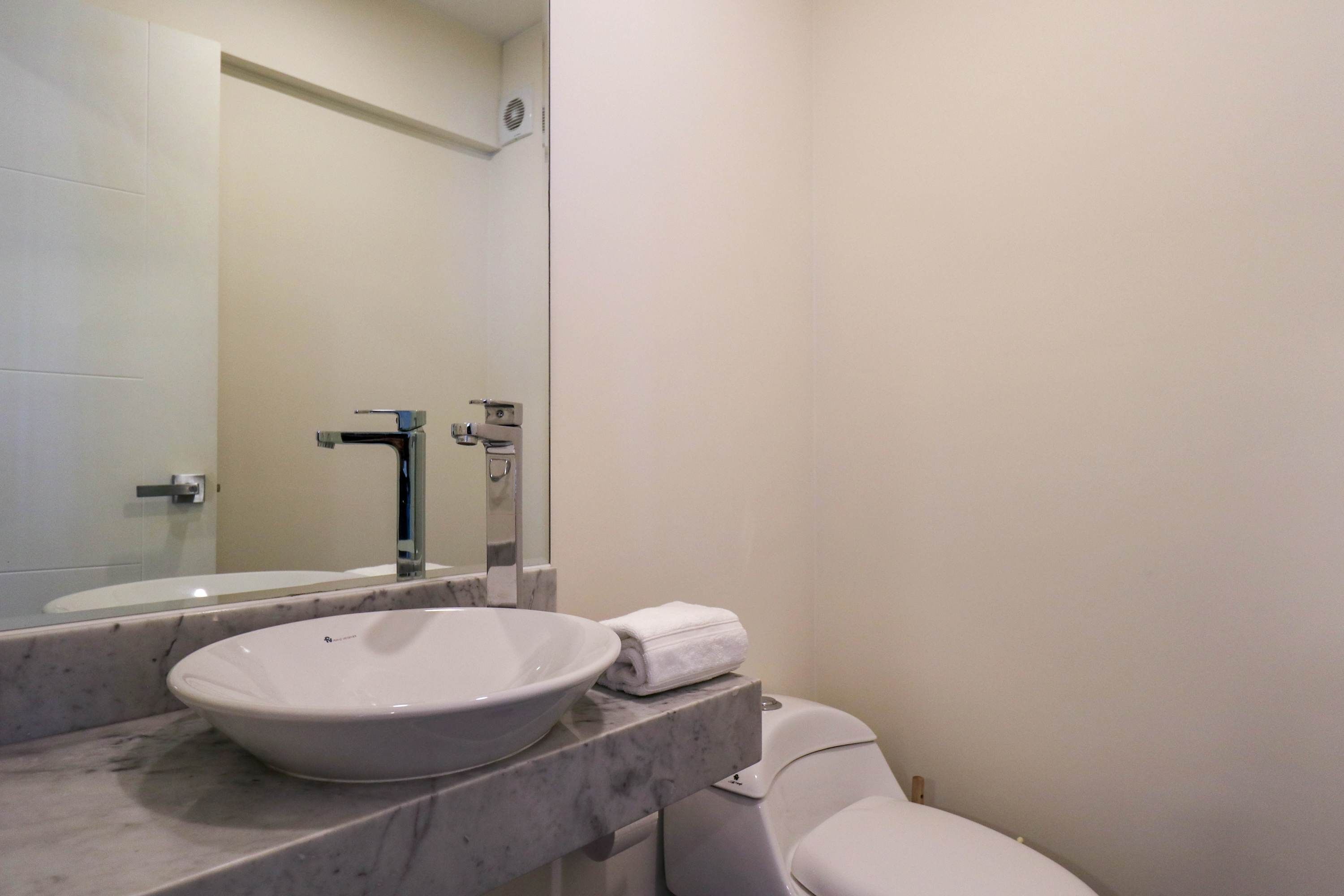 Un baño con lavamanos blanco, un espejo y un inodoro.