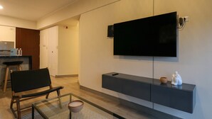 A modern living room with a flat-screen TV mounted on the wall, a dark console table with decorative items, a wooden bench, and a glass coffee table. - w Glorious 2BR w Balcony in San Isidro (Lima)