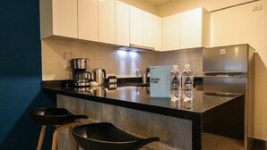 A modern kitchen with a black countertop, stainless steel appliances, and two black bar stools. - w Glorious 2BR w Balcony in San Isidro (Lima)