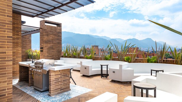 Eine Terrassengaststätte mit Grill, Sitzbereichen und Blick auf die Berge.