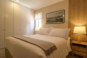 A bedroom with a bed, a nightstand with a lamp, a window with a view, and a door. - w Breathtaking 2BR With Balcony in Miraflores (Lima)