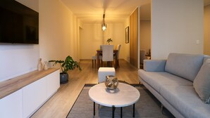 En moderne stue med sofa, sofabord og et spiseområde med stole og bord.
