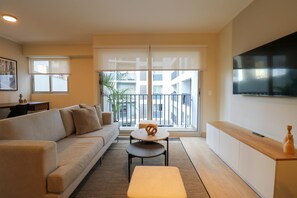 A modern living room with a sofa, a coffee table, and a TV mounted on the wall. - w Breathtaking 2BR With Balcony in Miraflores (Lima)