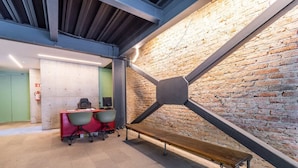 Un espacio de oficina moderno con pared de ladrillo, un escritorio con sillas y un banco de madera.