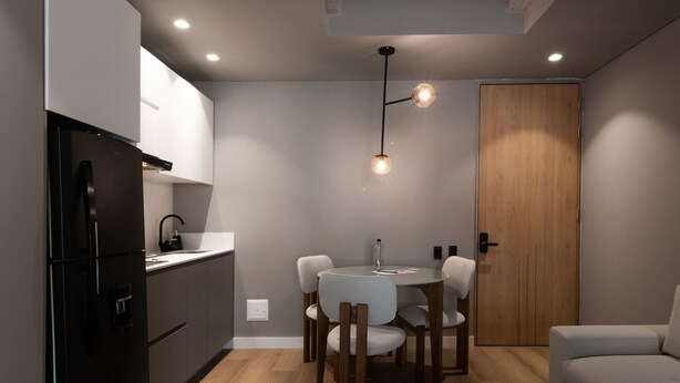 A compact kitchen with a black refrigerator, a wooden door, and a round dining table with chairs. - w Cozy Loft w/ Modern Balcony in Unicentro (Bogotá)