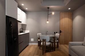 A compact kitchen with a black refrigerator, a wooden door, and a round dining table with chairs. - w Cozy Loft w/ Modern Balcony in Unicentro (Bogotá)