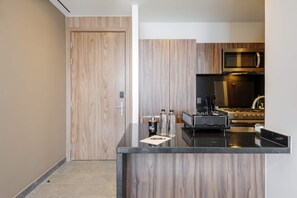 A modern kitchen with a wooden door, a black countertop, and stainless steel appliances. - w Luxurious 1BR w/ Amazing View in Cuauhtémoc (Mexico City)