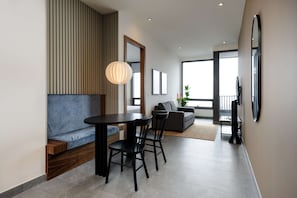 Una sala de estar moderna con comedor, sofá, televisor y un amplio ventanal.