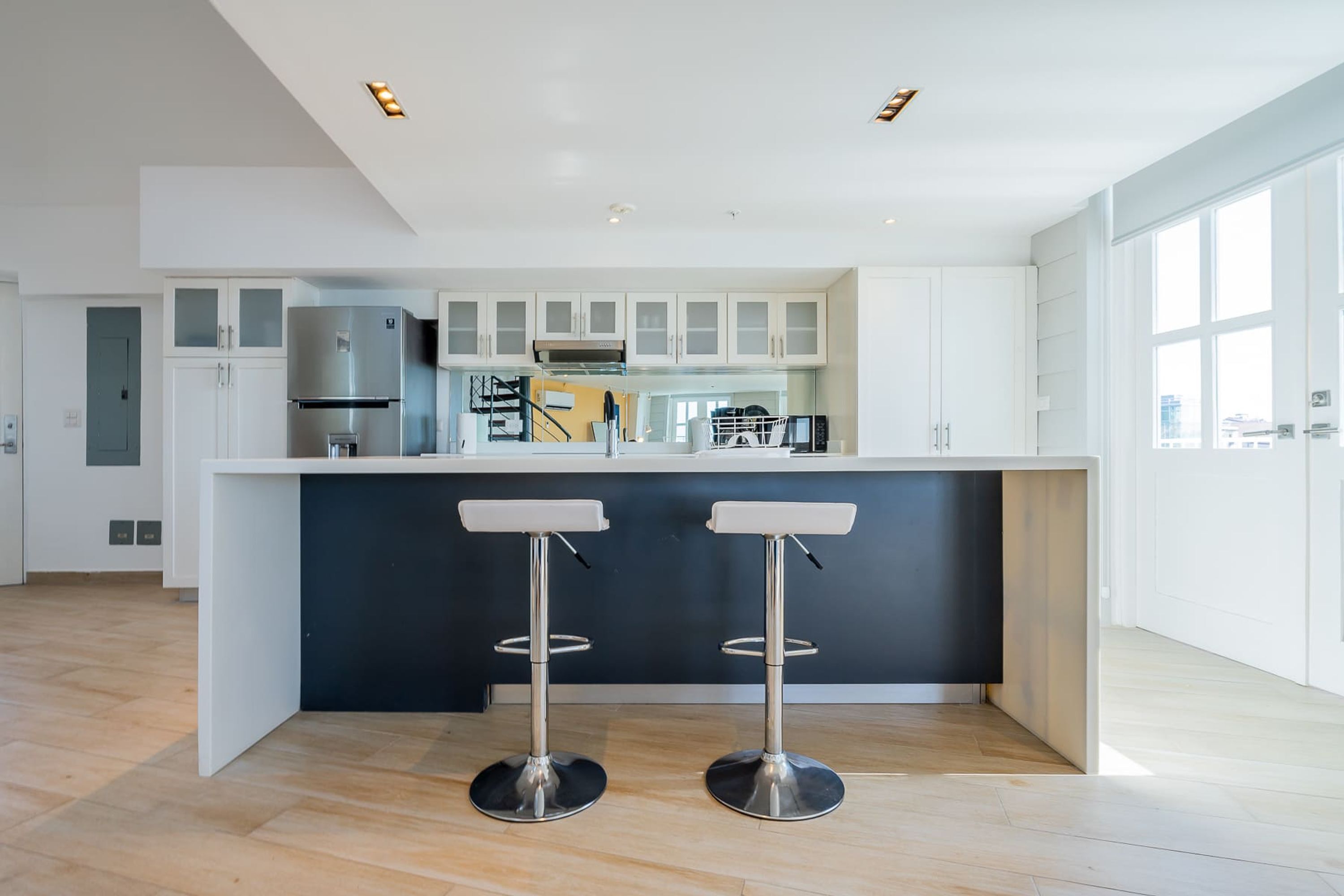 Cozinha moderna com ilha central, eletrodomésticos de aço inoxidável e uma janela ampla.
