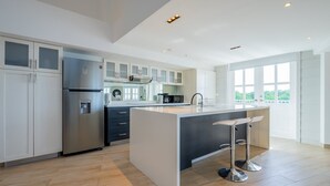 A modern kitchen with a central island, stainless steel appliances, and a large window providing natural light.
