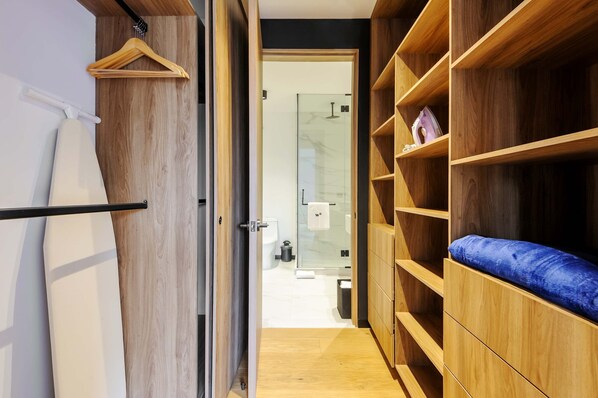 A modern bathroom with a glass shower, wooden shelving, and a blue cushioned bench. - w Deluxe 1BR With Elegant Balcony in Roma Nte (Mexico City)