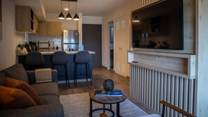 A modern living room with a sofa, a coffee table, and a TV mounted on the wall. - w Great 1BR Apartment in Miraflores (Lima)