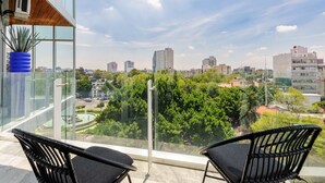 Un balcon offrant une vue sur le paysage urbain, avec ses bâtiments et sa verdure.
