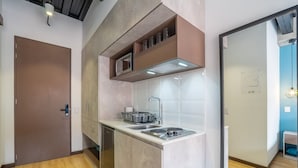 Una cucina compatta con forno a microonde, lavello e fornello, una porta e vista su un'altra stanza.
