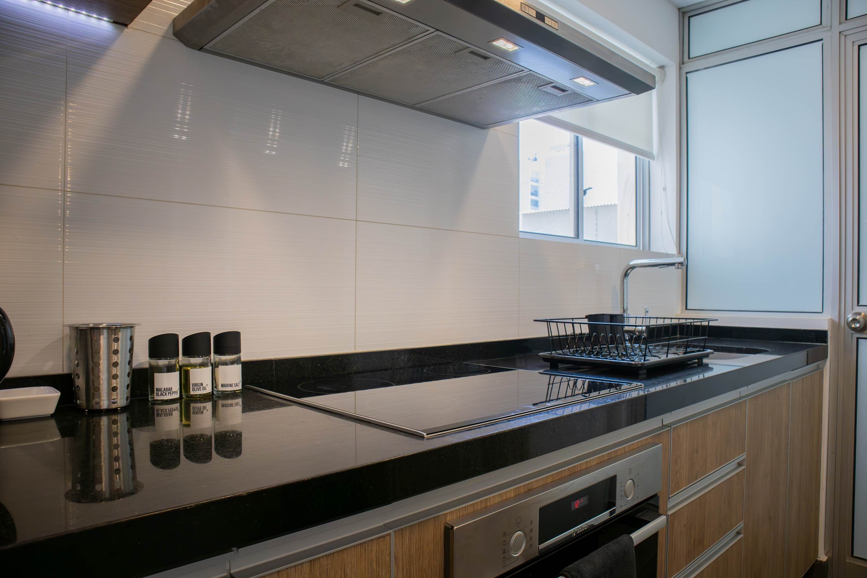 Una cucina moderna con piano di lavoro nero, elettrodomestici in acciaio inossidabile e una finestra che lascia entrare luce naturale.