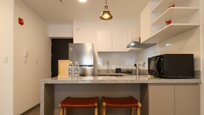 A modern kitchen with a granite countertop, stainless steel appliances, and wooden stools. - w Captivating 1BR w Perfect Terrace in Cusco (Cusco)