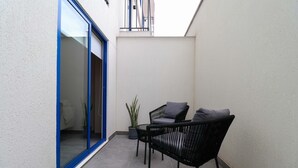 A small outdoor patio with a sliding glass door, a potted plant, and two black wicker chairs with cushions. - w Captivating 1BR w Perfect Terrace in Cusco (Cusco)