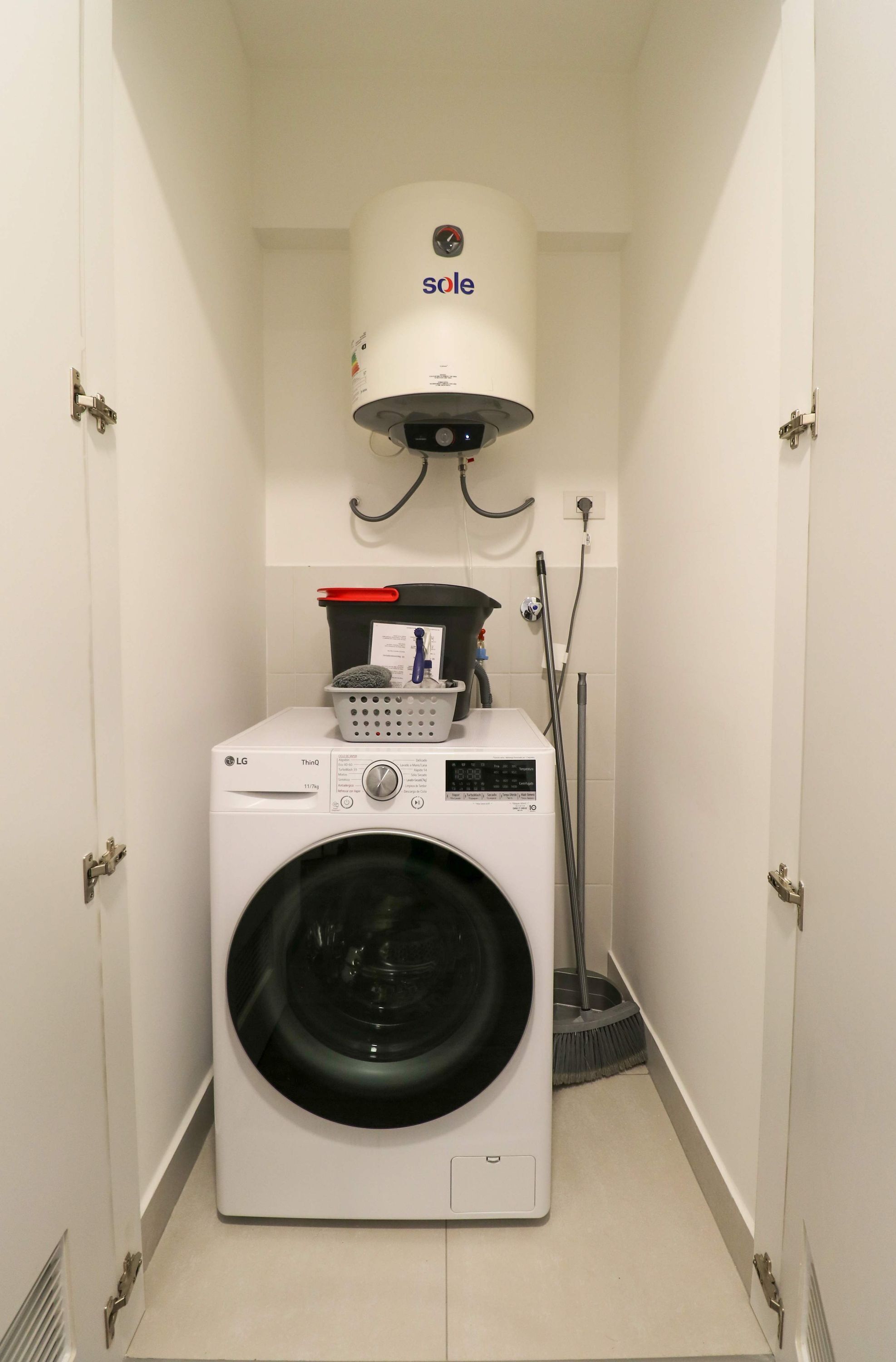 A laundry room with a front-loading LG ThinQ washer and dryer, a Sole water heater, and a mop.