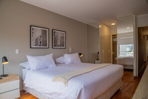 A bedroom with a large bed, two bedside tables, a nightstand, a lamp, and two framed pictures on the wall. - Beautiful 3BR With Fantastic Deco in Miraflores (Lima)