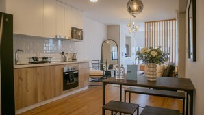 A modern kitchen with wooden cabinets, a built-in oven, and a dining area with a wooden table and bench. - w Stunning 1BR w Great Deco in San Isidro (Lima)