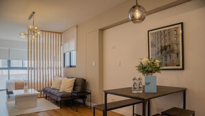A modern living room with a sofa, coffee table, and a dining table with benches. - w Stunning 1BR w Great Deco in San Isidro (Lima)