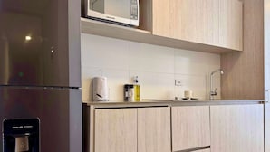 Cocina moderna con refrigerador empotrado, microondas y lavamanos con grifo.