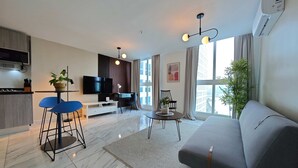 A modern living room with a sofa, TV, dining area, and kitchen. - w Awesome 1BR w Great Deco in Avenida Balboa (Panama City)