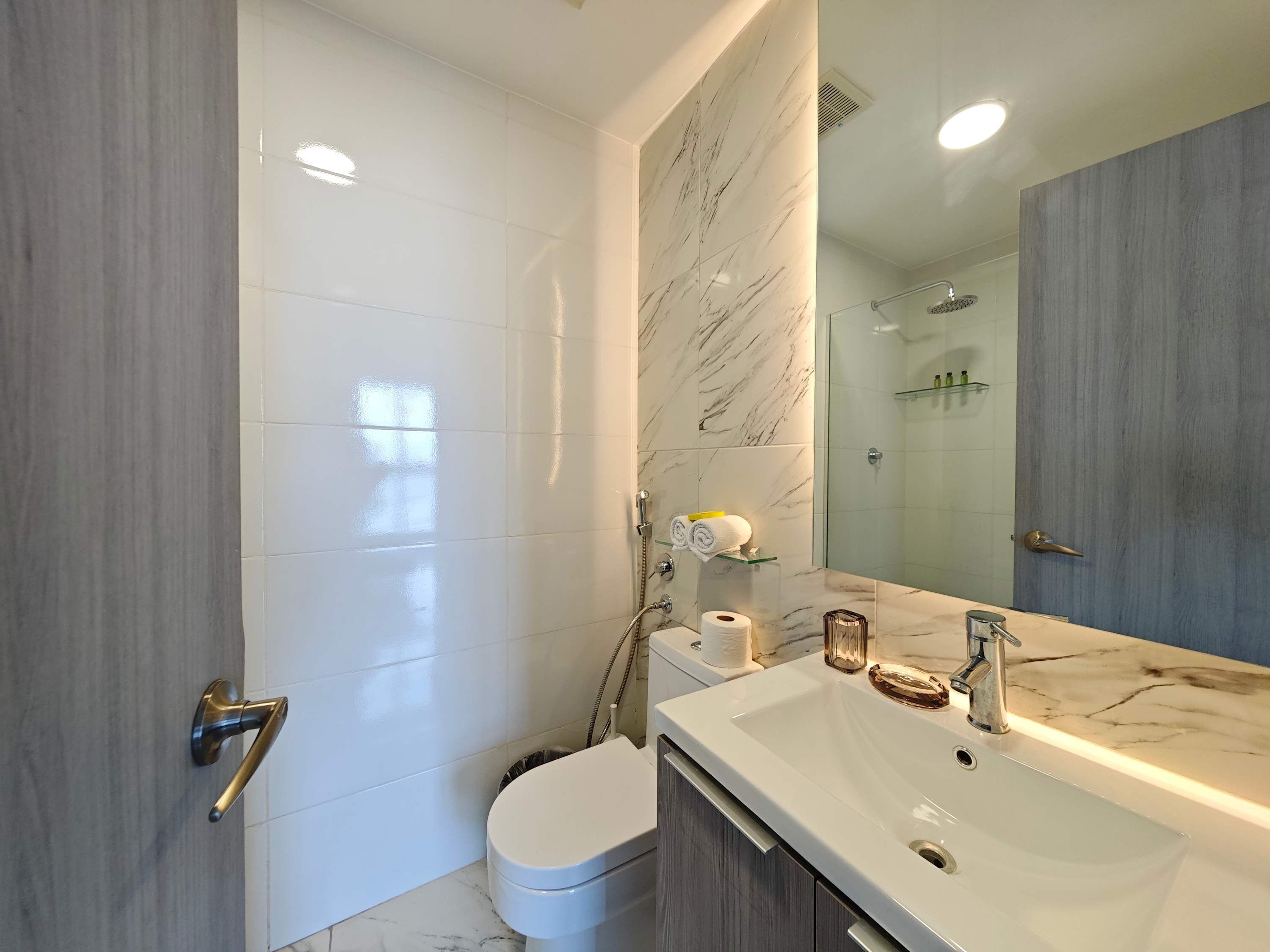 Een moderne badkamer met een grote spiegel, een wastafel en een toilet.