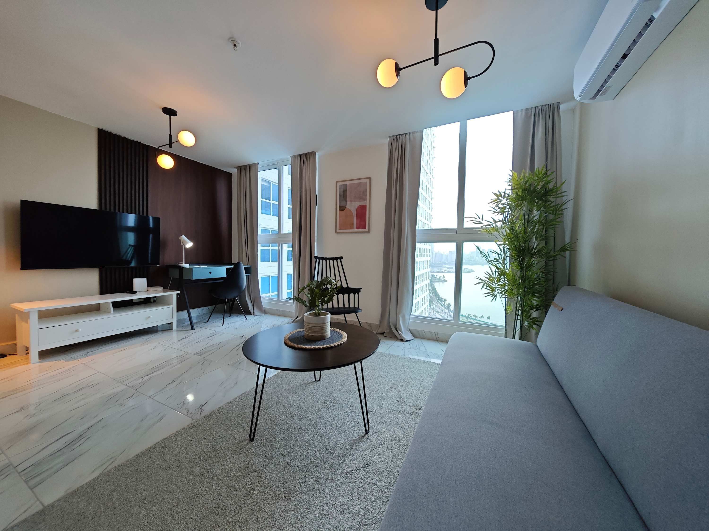 Una sala de estar moderna con un televisor de pantalla plana, un sofá, una mesa de centro y un escritorio con una silla.