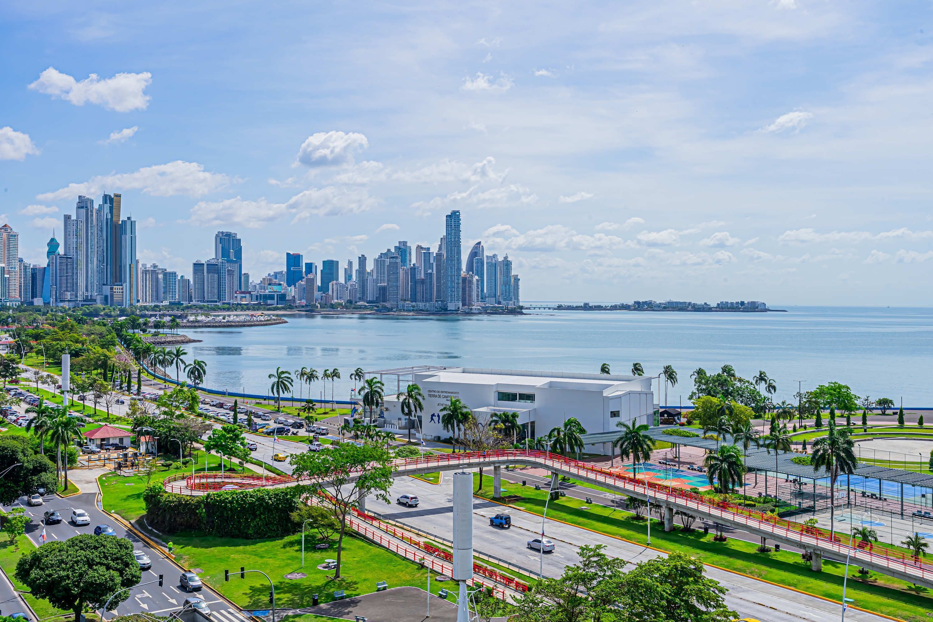 A cityscape with a modern skyline, a marina, and a bridge connecting two areas.