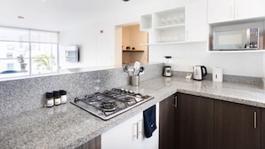 A modern kitchen with granite countertops, a gas stove, a microwave, and a coffee maker. There are cabinets and a window providing natural light. - w Great 3BR Duplex With Terrace in Miraflores (Lima)