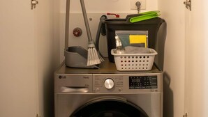 Une petite buanderie équipée d’un lave-linge, d’un sèche-linge et d’un chauffe-eau sur lequel est apposée l’étiquette « sole ».
