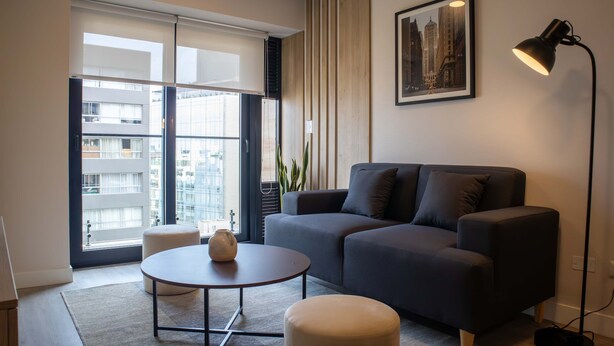 Un salon moderne avec un canapé gris, une table basse ronde et un lampadaire.