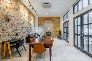 Un intérieur moderne avec des murs en pierre, un coin repas et de grandes fenêtres.