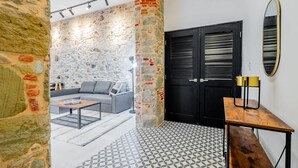 A modern interior with a stone wall, a black door, a round mirror, and a grey sofa. - w Contemporary 1BR in Plaza Catedral (Panama City)