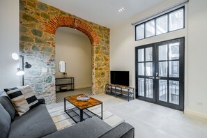 Una sala de estar con una pared de piedra, chimenea, sofá, mesa de centro y un amplio ventanal.
