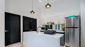 A modern kitchen with a central island, stainless steel appliances, pendant lighting, and white cabinetry. - w Contemporary 1BR in Plaza Catedral (Panama City)