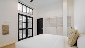 A bedroom with a bed, a ceiling fan, a window with blinds, a door, and a wall-mounted macrame piece. - w Contemporary 1BR in Plaza Catedral (Panama City)