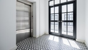 A hallway with a patterned floor, a door, and a window with a view of the outside. - w Contemporary 1BR in Plaza Catedral (Panama City)