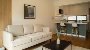 A modern living room with a sofa, a coffee table, and a kitchen area with a bar counter and stools. - w Atonishing 1BR w Great Deco in San Isidro (Lima)