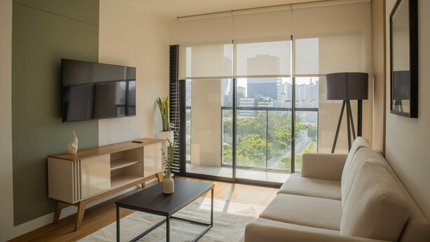 A modern living room with a flat-screen TV, a wooden console table, a beige sofa, and a floor lamp. - w Atonishing 1BR w Great Deco in San Isidro (Lima)