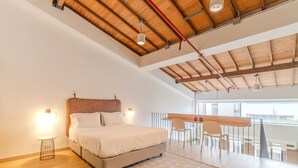 A spacious bedroom with a large bed, a wooden ceiling, and a balcony with a dining area. - w Stylish Duplex in Laureles (Medellín)
